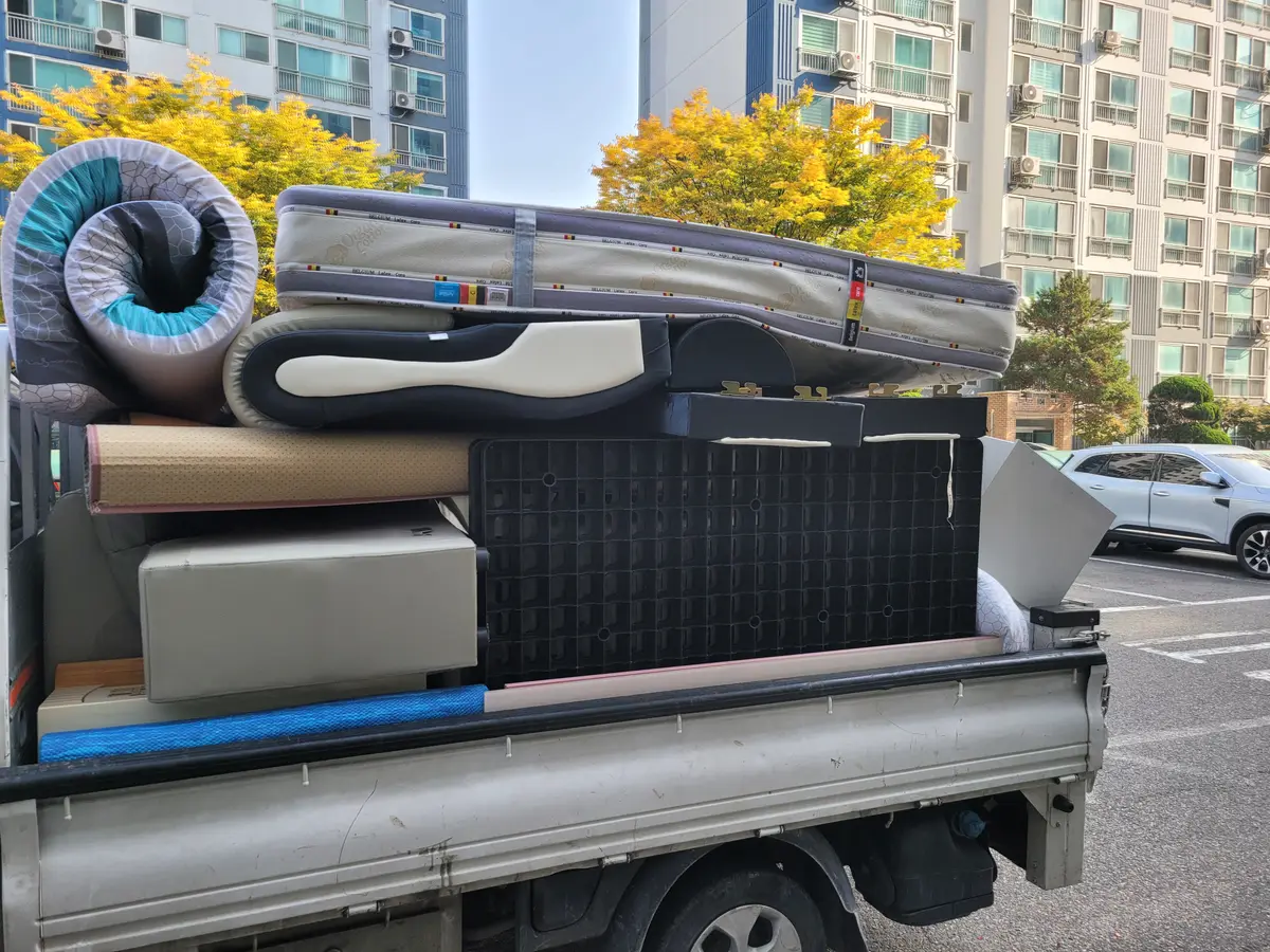 매트리스와 소파, 가구를 높이 쌓아 실은 트럭 적재함